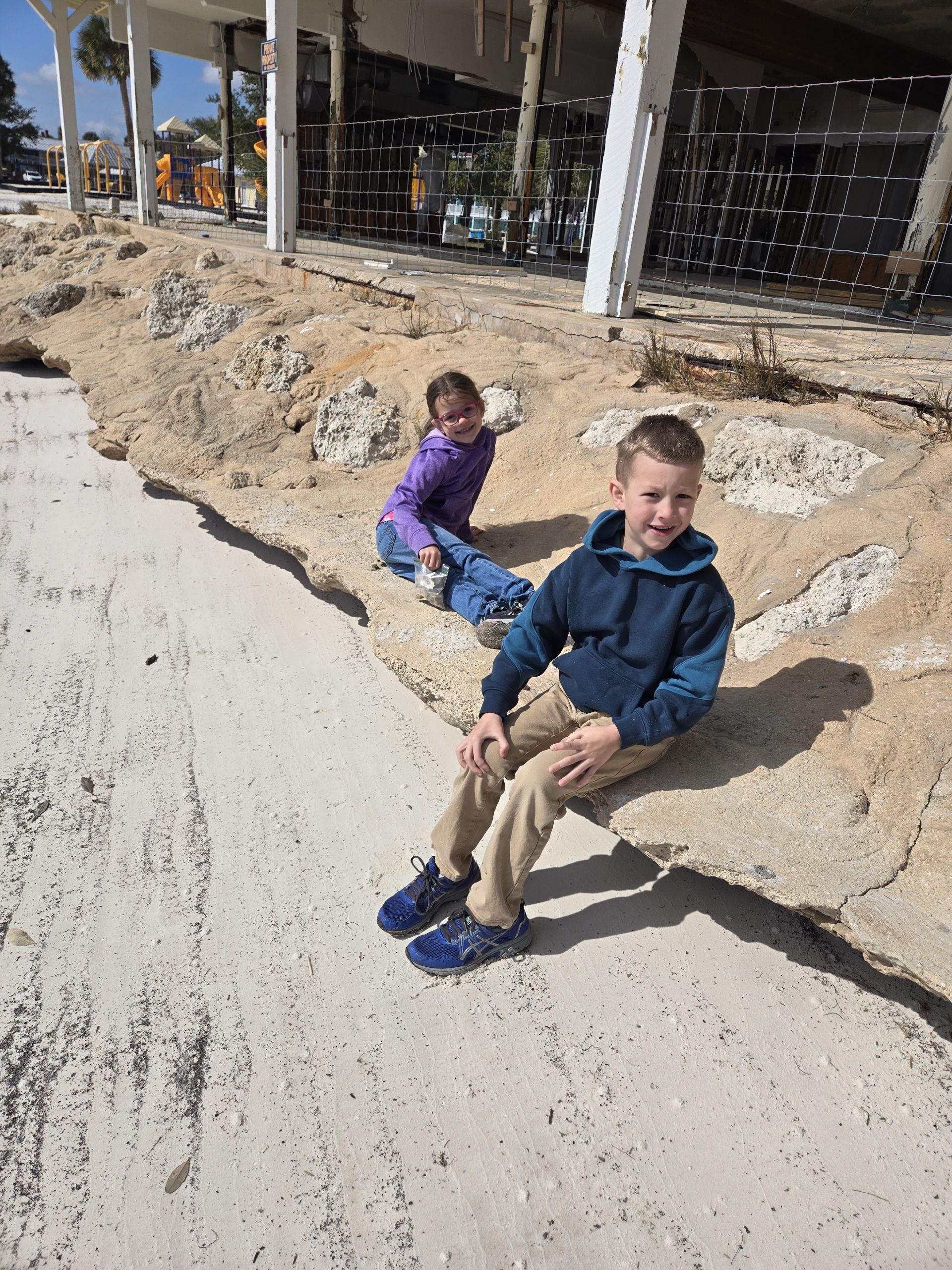 JD and Ali sitting on limestone rocks at a park